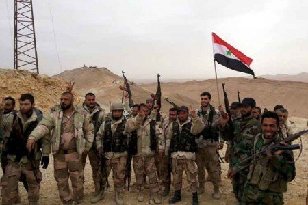 Forces loyal to Syria's President Bashar al-Assad flash victory signs and carry a Syrian national flag on the edge of the historic city of Palmyra in Homs Governorate, in this file handout picture provided by SANA on March 26, 2016. Syrian government forces recaptured Palmyra on March 27, state media and a monitoring group said, inflicting a significant defeat on the Islamic State group which had controlled the desert city since May last year. REUTERS/SANA/Handout via Reuters/Files ATTENTION EDITORS - THIS PICTURE WAS PROVIDED BY A THIRD PARTY. REUTERS IS UNABLE TO INDEPENDENTLY VERIFY THE AUTHENTICITY, CONTENT, LOCATION OR DATE OF THIS IMAGE. FOR EDITORIAL USE ONLY. NOT FOR SALE FOR MARKETING OR ADVERTISING CAMPAIGNS. THIS PICTURE IS DISTRIBUTED EXACTLY AS RECEIVED BY REUTERS, AS A SERVICE TO CLIENTS