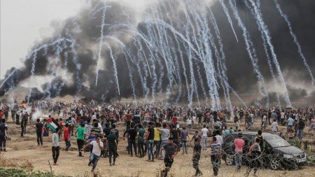 TOPSHOT - Palestinian protesters flee from incoming teargas canisters during clashes with Israeli forces along the border with the Gaza strip east of Gaza City on May 4 2018 on the sixth straight Friday of mass demonstrations calling for the right to return to their historic homelands AFP PHOTO MAHMUD HAMS